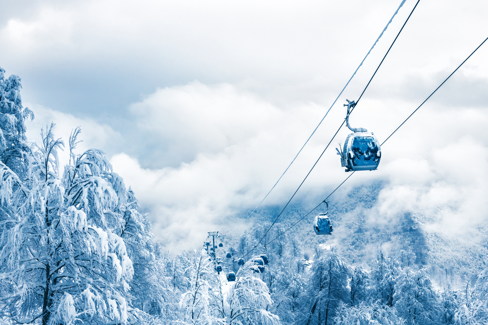 Ski gondola above snowy mountains